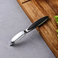 Stainless steel peeler and grater kitchen tools for food prep.