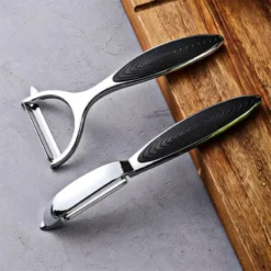 Stainless steel peeler and grater kitchen tools for food prep.